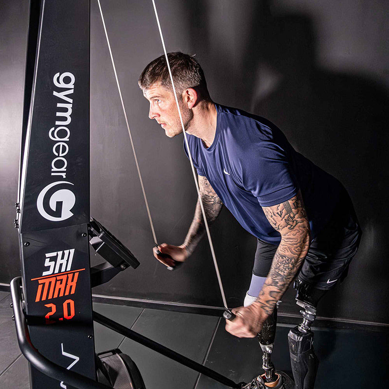 Man using a resistance training machine with 'Gymgear' branding in a gym setting.