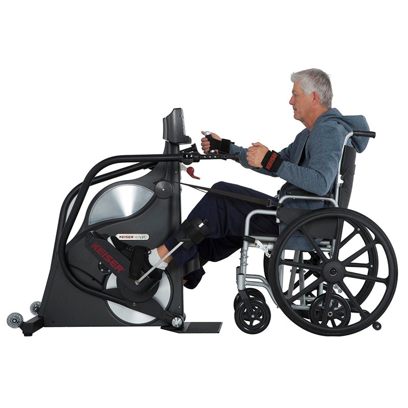 Person using a wheelchair with an attached Keiser M7i Total Body Wheelchair Stepper exercise bike on a white background