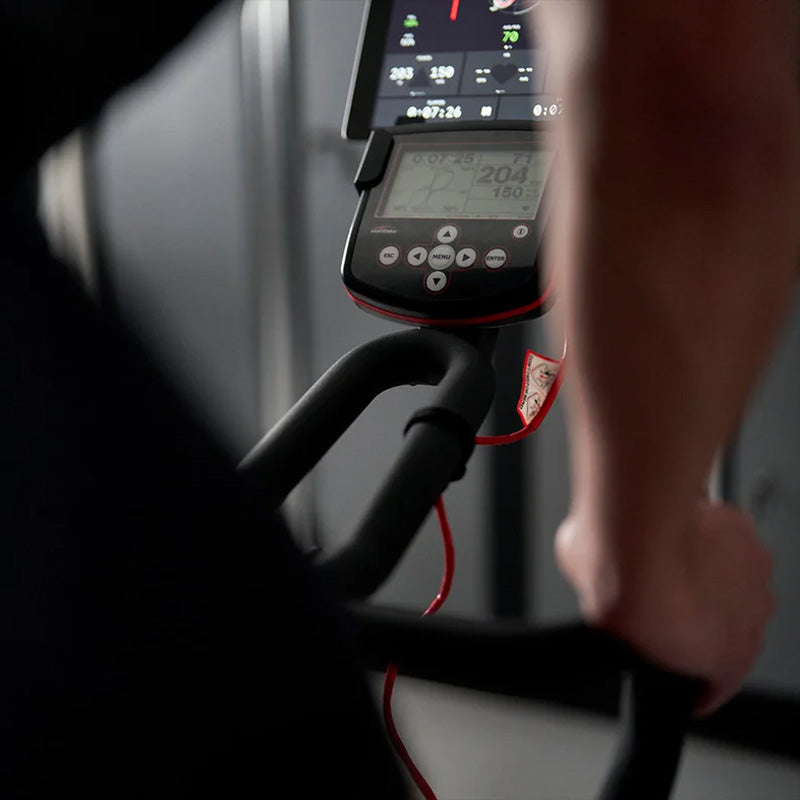 Close-up of a person using the Wattbike pro trainer exercise bike with a digital display showing workout metrics.