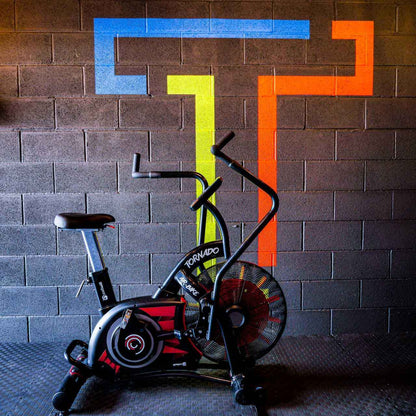 Gym Gear Tornado Airbike exercise bike against a brick wall with colourful geometric patterns