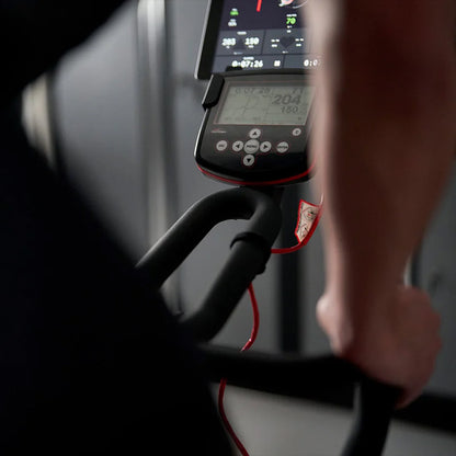Close-up of a person using the Wattbike pro trainer exercise bike with a digital display showing workout metrics.