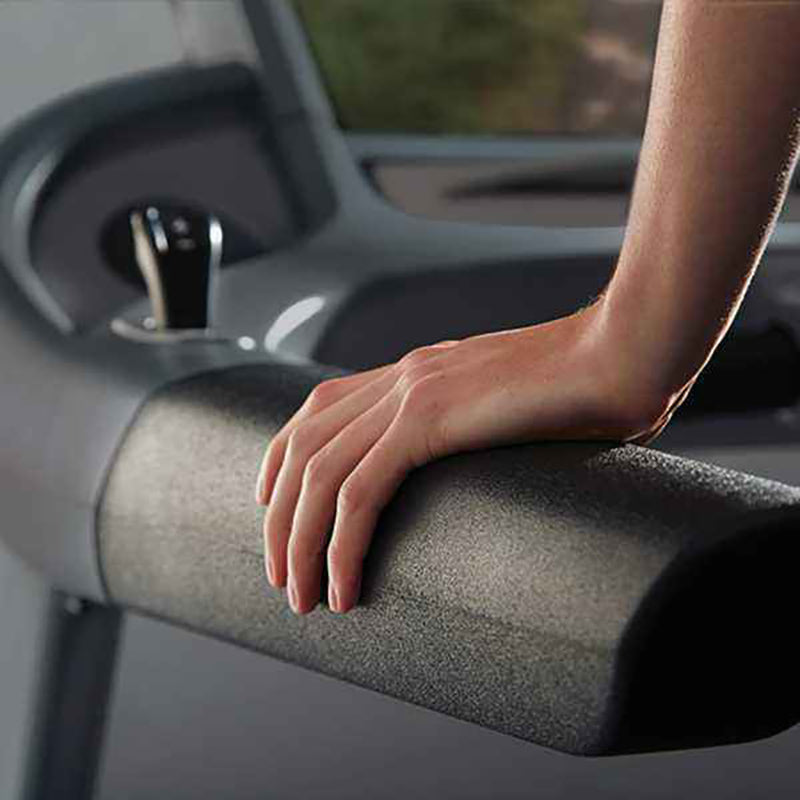 Gym Gear T98e Treadmill with hand resting on safety armrest with a blurred interior background